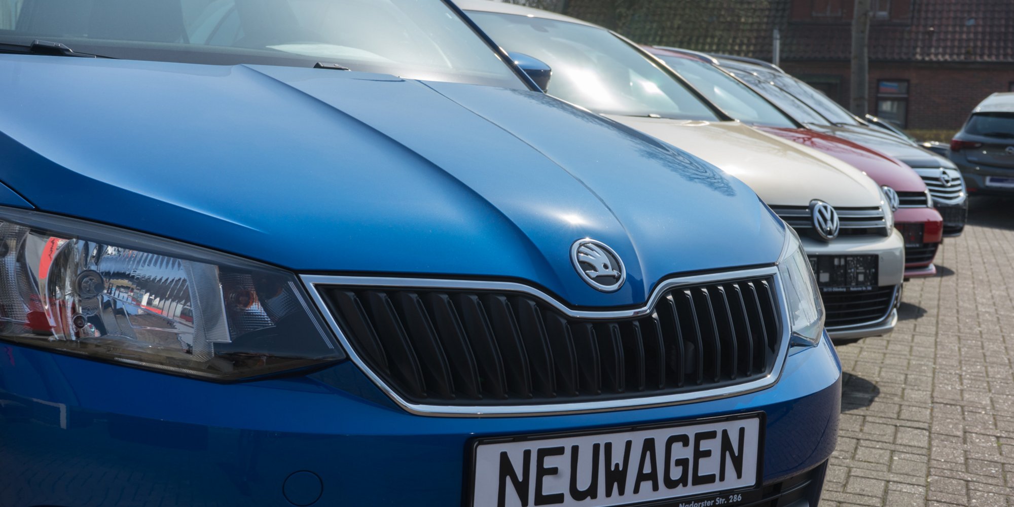 Mehrere Autos stehen dicht aneinandergereiht auf einem Parkplatz, im Vordergrund ein blauer Škoda.